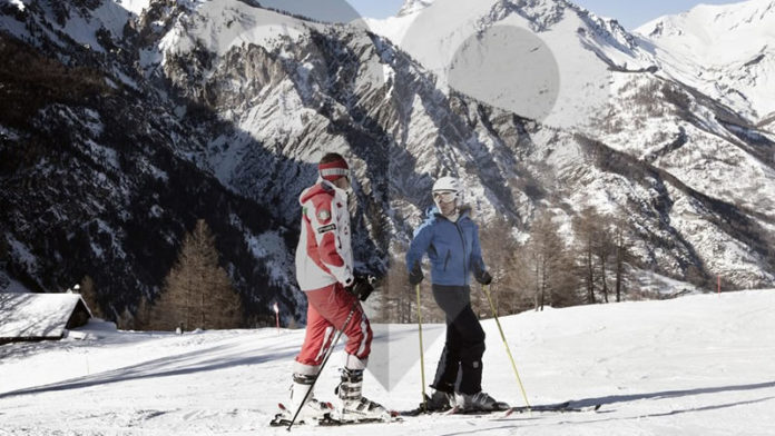 A couple is skiing among slopes and mountains