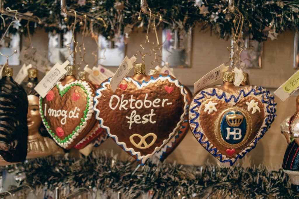 Three Christmas ornaments and one in the centre says Oktoberfest - which is a fall festival celebrated in Munich, Germany. 