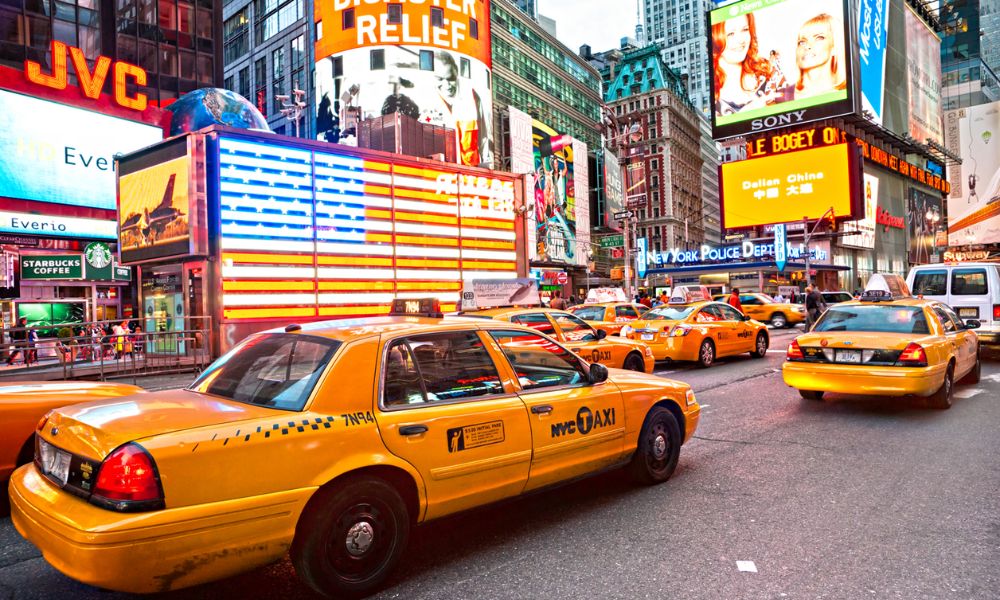 A scene from New York from the holiday offer package - the iconic yellow cabs, bright city buildings and high rises, and billboards and a sign of the New York Police Department 