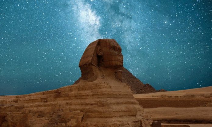 The famous sphinx head of one of the most well known pyramids in Egypt set against a nice, blue sky filled with light and stars