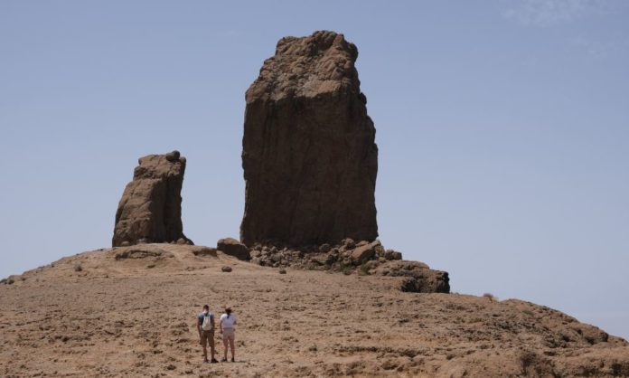 Two rock formations and two hikers hiking towards it in Gran Canaria