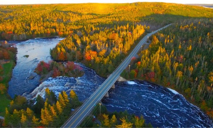 A long bridge and road across a water body and you can see the beauty of fall colours in this road trip to Nova Scotia