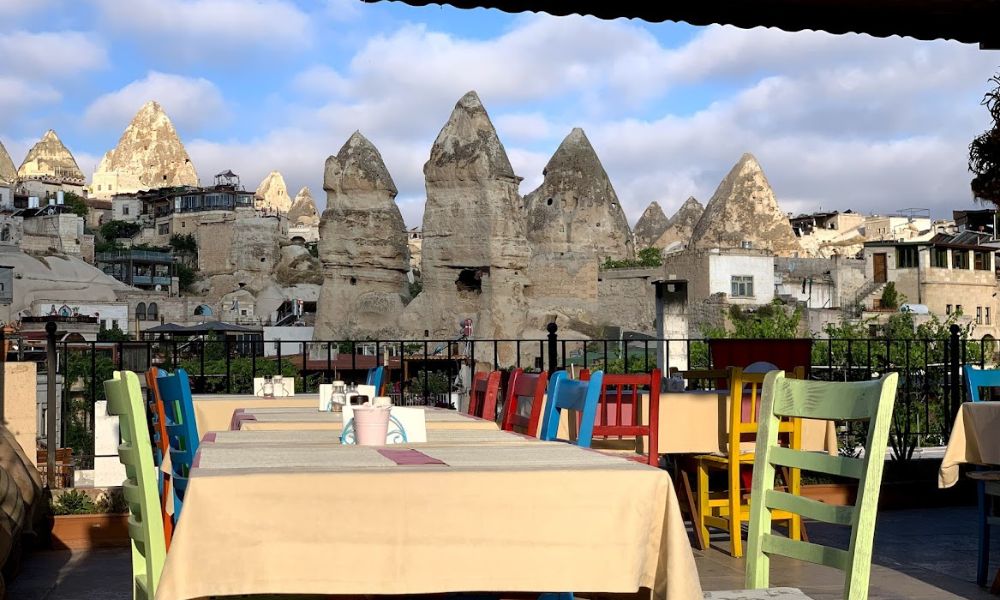 A table and colourful chairs are set out and you can see the fairy chimneys of Cappadocia surrounding the tables 