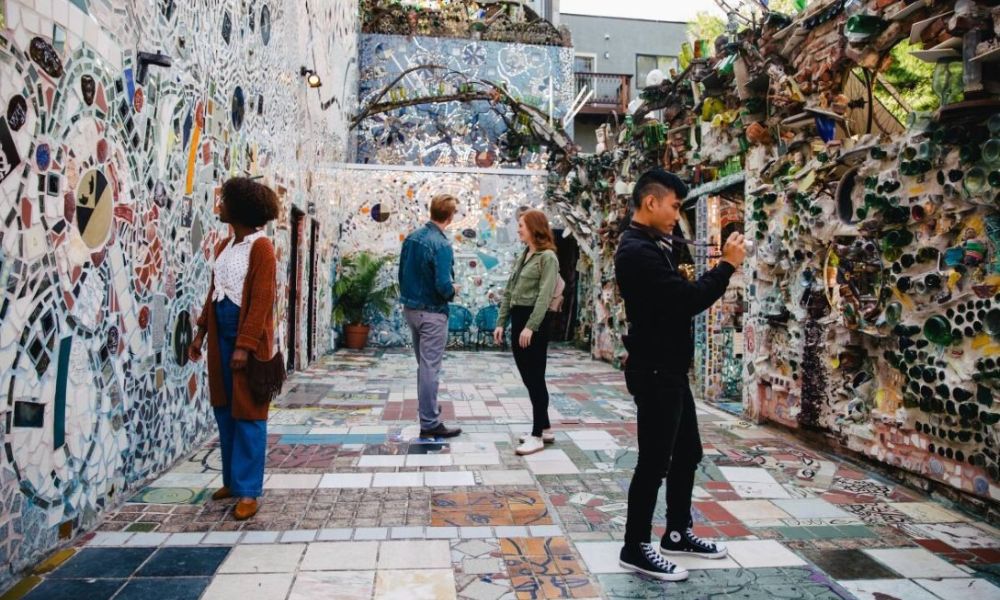 People strolling through Philadelphia’s Magic Gardens, looking at the mosaic on the walls and also taking photographs