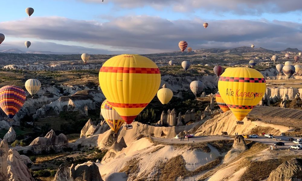 Different hot air balloons are flying over the Cappadocia skyline, and you can see fairy chimneys and unique landscape