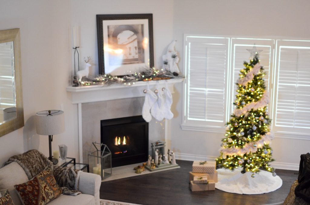 White stockings over a fireplace and a tree that is also decorated in white fur - traditional customs and decor for a house along with nativity scene in white figurines too