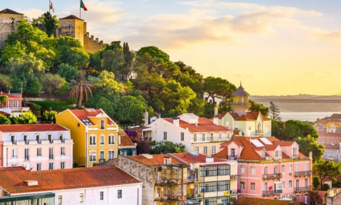 You see Lisbon's landscape with colourful building perched on a hill - Lisbon is good for digital nomads