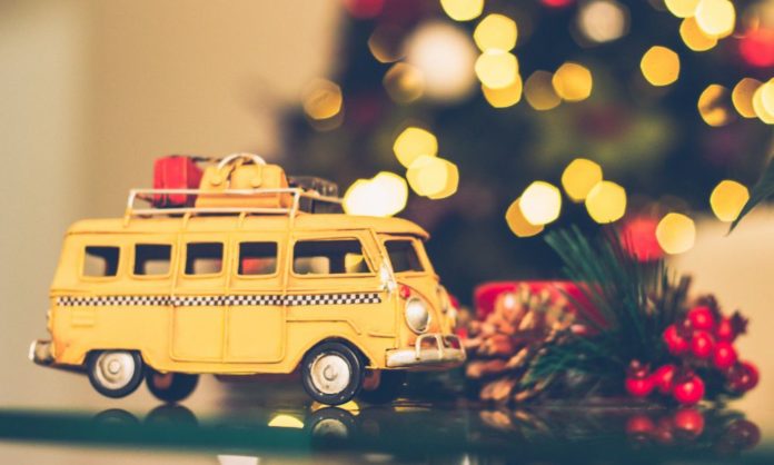 A small toy yellow campervan and festive trees - a metaphorical way to show Christmas travel