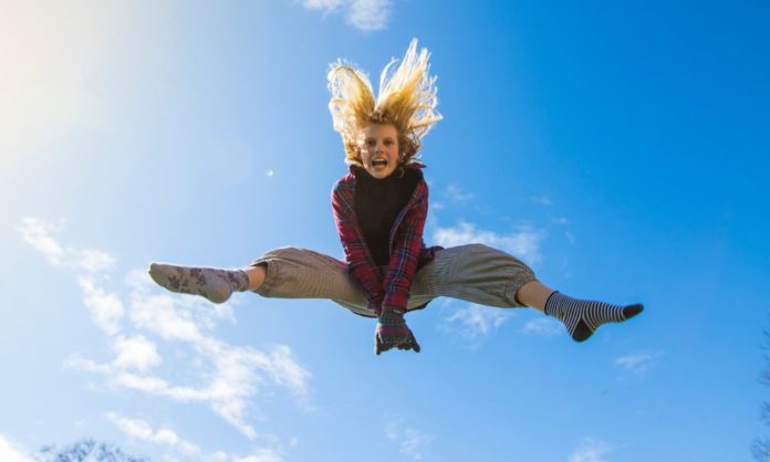 A woman jumps high in the sky in delight of securing a good deal