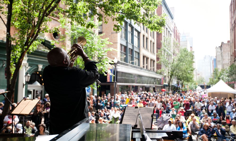 A huge crowd for the Jazz Festival in Pittsburgh and you can see buildings, people and a man who is performing
