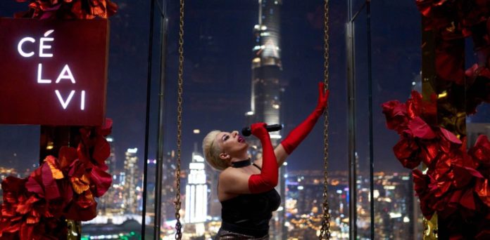 A woman in cabaret dress swinging at the world's best rooftop restaurant 2022 for Culinary Awards - which is in Dubai and called CÉ LA VI @ Address Sky View (UAE)