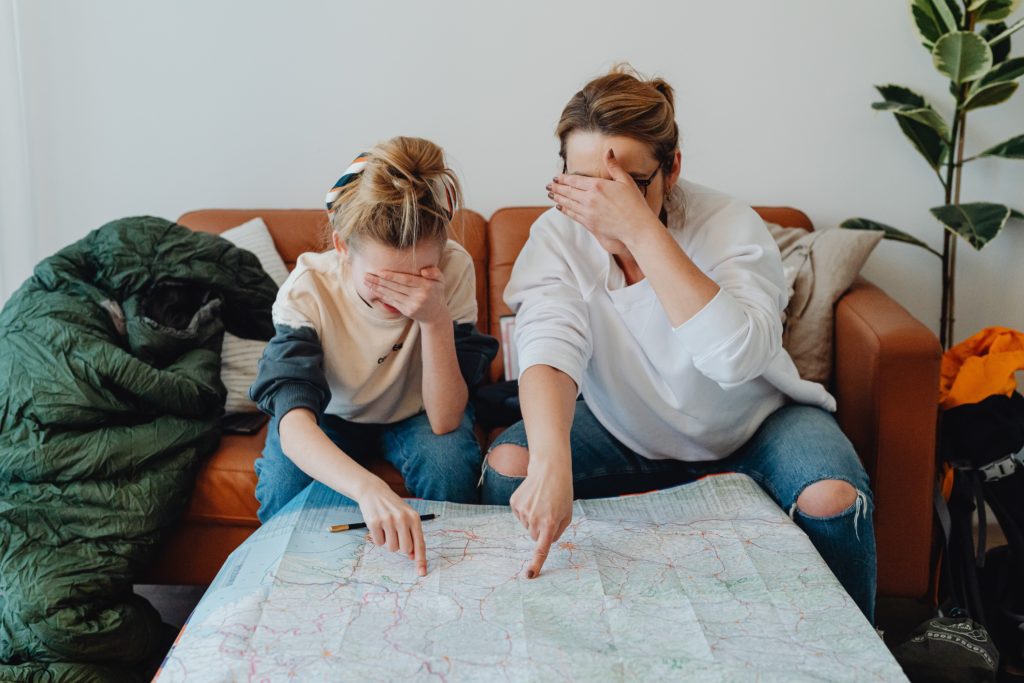 Mother daughter close their eyes and point to a map on a table