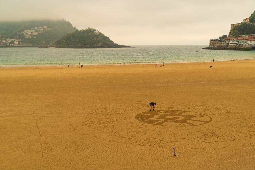 Aerial view of a man drawing in sand on the coast in San Sebastian, Spain